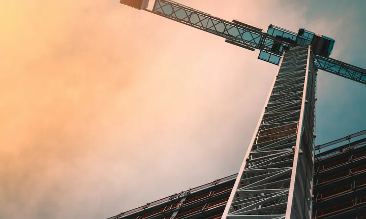 Tower crane against a dramatic sky — representative boom-and-lift equipment akin to aerial and utility trucks