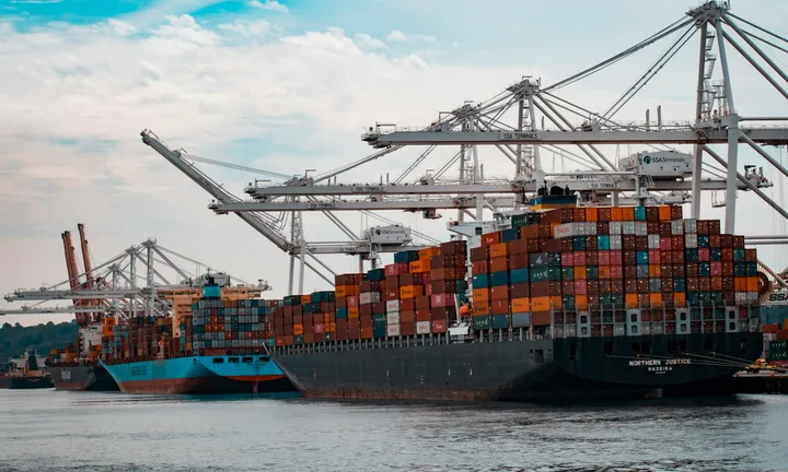 Cargo ship under gantry cranes at a shipping port — water-infrastructure setting comparable to lock and dam sites